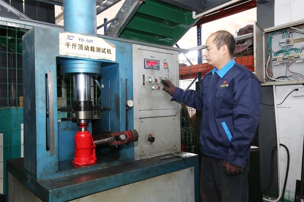 Technician load-testing a hydraulic bottle jack on the factory test press